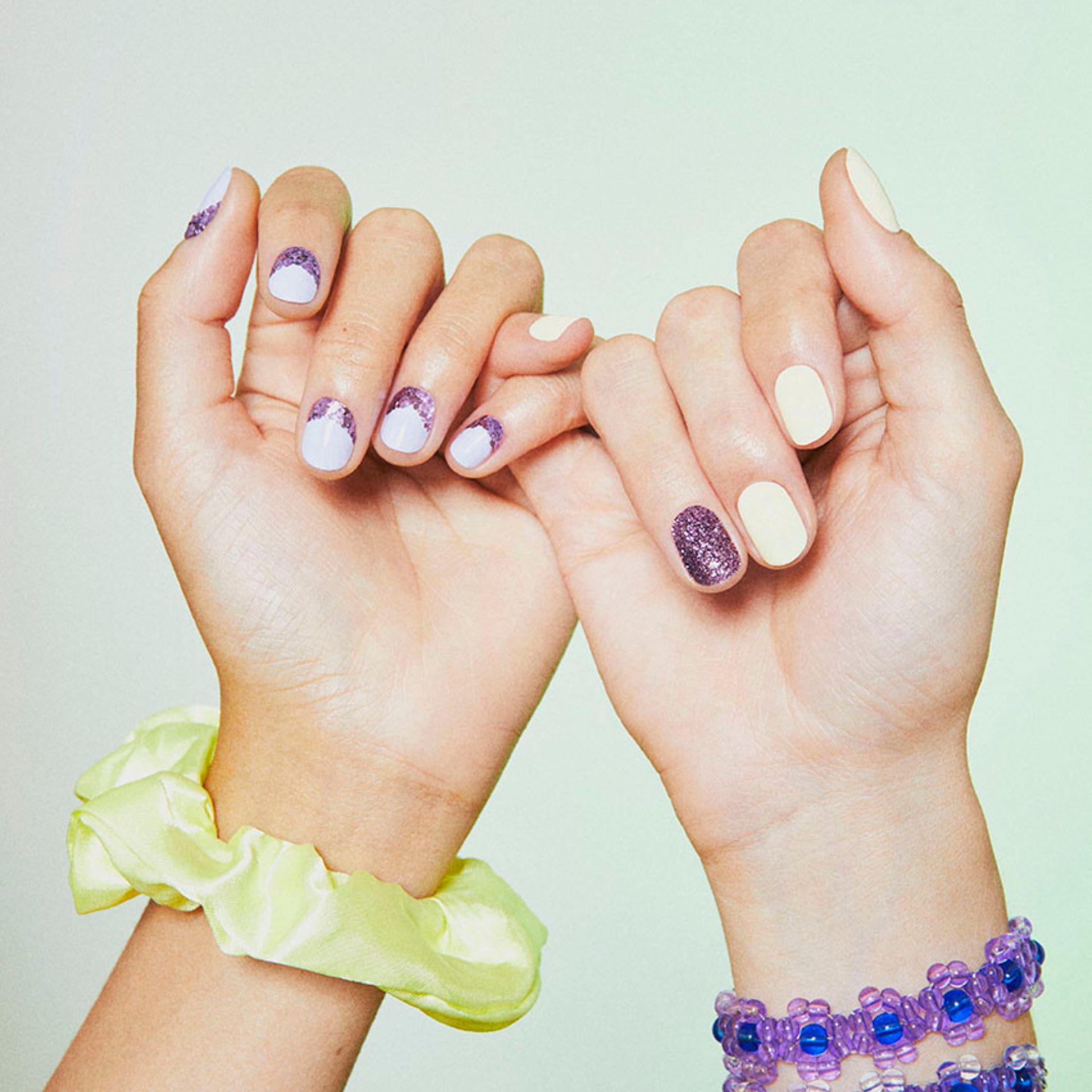Manucure paillettes avec vernis jaune pastel et petites paillettes violettes