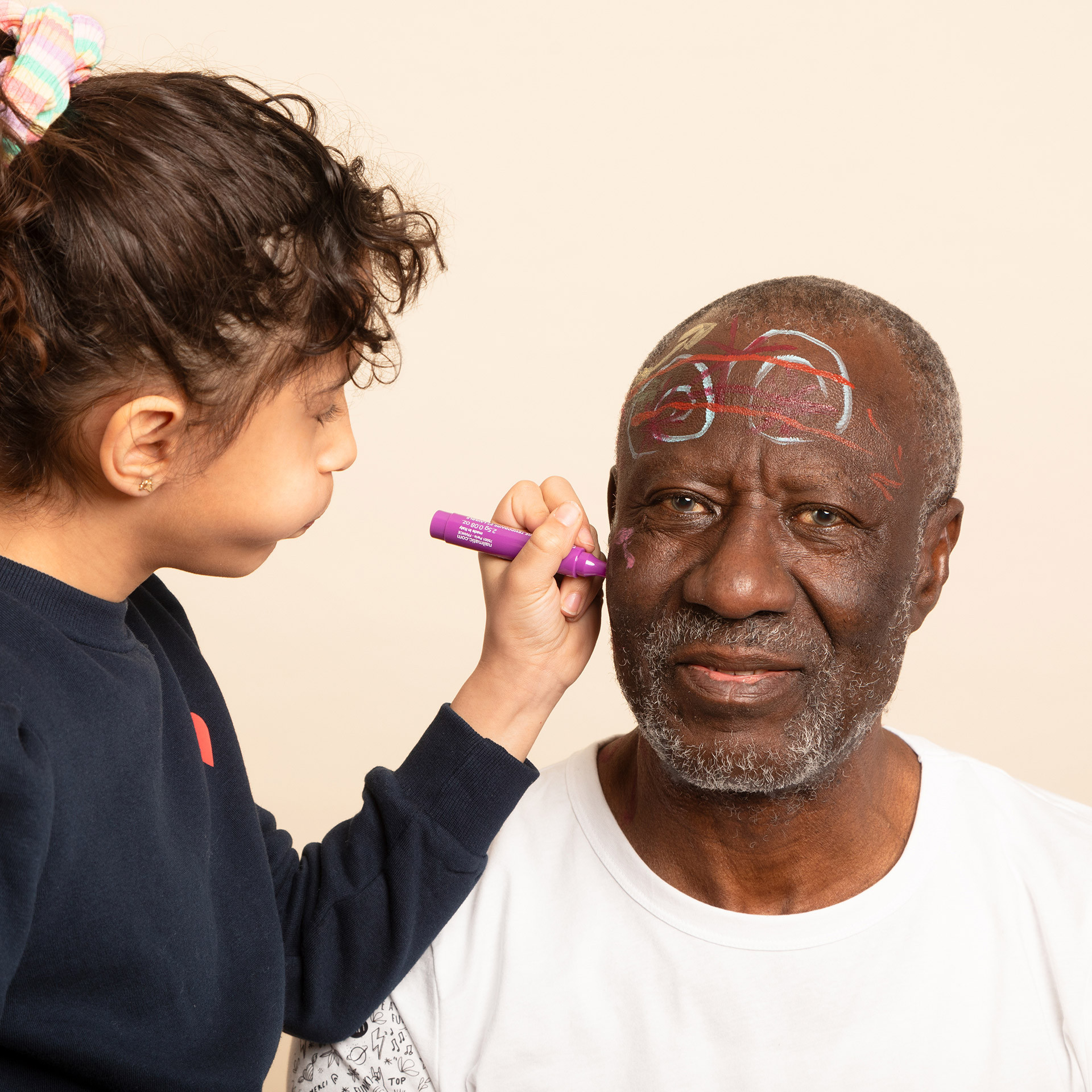 Enfant qui dessine sur visage homme avec feutre de tatouage temporaire violet