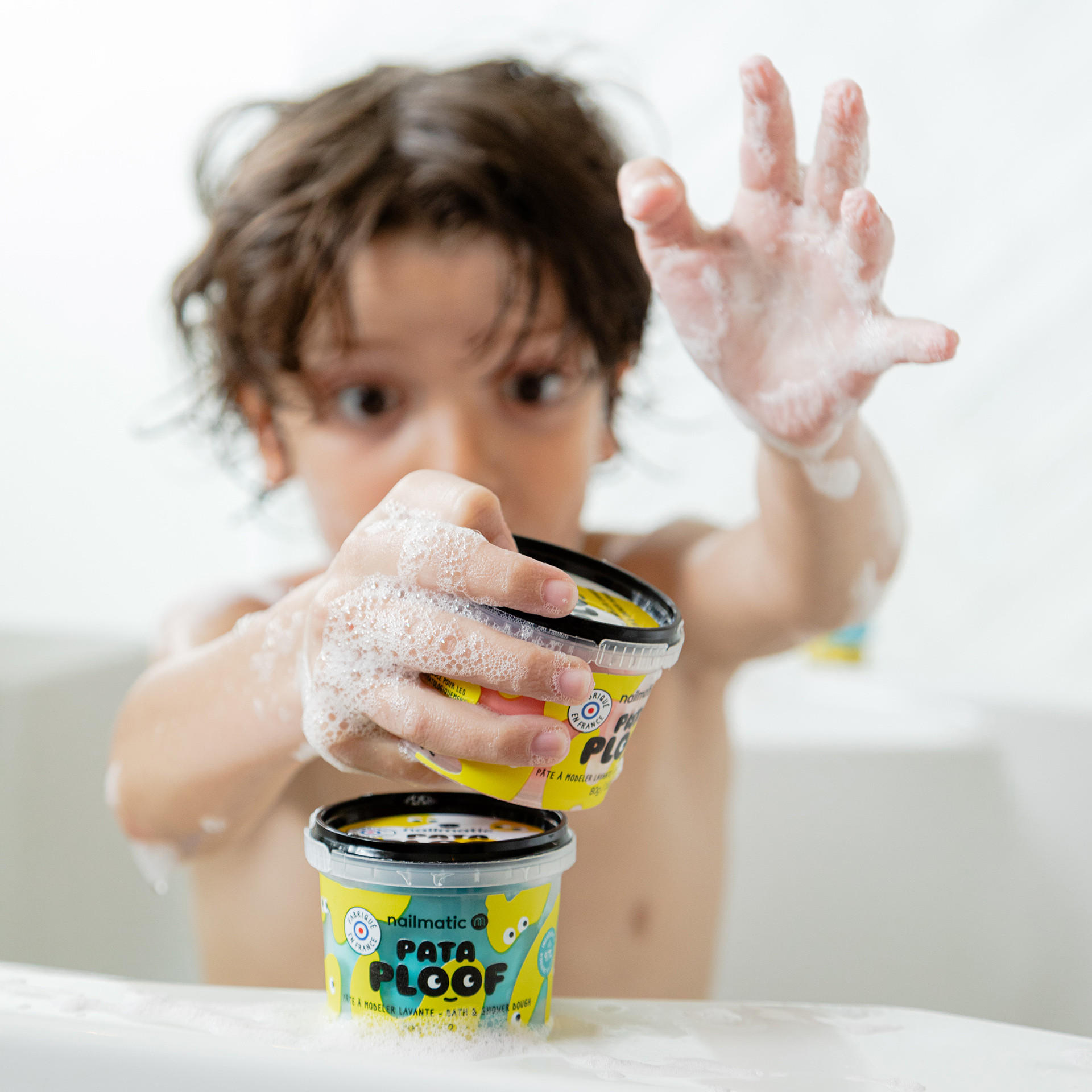 Enfant dans le bain qui joue avec de la pâte à modeler bleue Pataploof